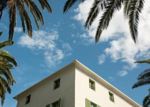 厄尔巴隆加Demeure Castel Brando Hôtel & Spa的前方有棕榈树的白色建筑