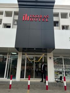 金沙萨Ixoras Hotel Victoire的站在酒店外的身着西装的男人