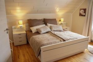 黑伦塔尔Ferienhaus Eifelwind Kamberg的一间卧室配有一张带两盏灯的大型白色床。