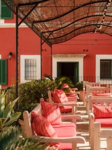 厄尔巴隆加Demeure Castel Brando Hôtel & Spa的红色建筑前的一排躺椅