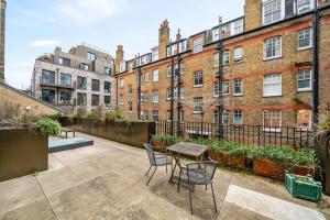 伦敦Chic Urban Retreat 1 Bedroom Gem in Covent Garden 3AB的建筑前方带桌椅的天井