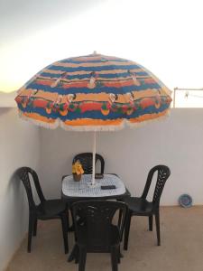 西迪伊夫尼Panorama guest house的一张桌子、两把椅子和一张桌子及一把雨伞