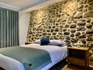库斯科Casa Encuentro San Blas的一间卧室设有石墙和一张床