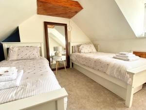 赫默尔亨普斯特德Bumblebee Cottage - Cosy Cottage in Area of Outstanding Natural Beauty的阁楼卧室设有两张床铺和镜子