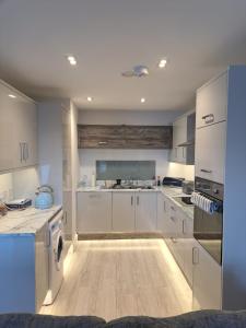 波特拉什Royal Atlantic View Apartment的厨房铺有木地板,配有白色橱柜。