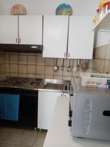 兰佩杜萨Splendido appartamento a Lampedusa, con terrazzo !的厨房配有白色橱柜、水槽和炉灶。