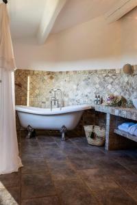 圣弗洛朗Hôtel La Dimora & Spa的带浴缸的浴室和石墙