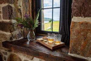 阿勒浦The Wreck - Lochside cottage Dog Friendly的窗台,带两杯玻璃和花瓶