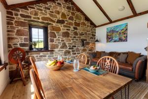 阿勒浦The Wreck - Lochside cottage Dog Friendly的客厅设有木桌和石墙