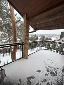 Radikiai House的雪覆盖的甲板上设有栅栏和一棵树
