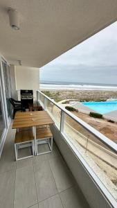 拉塞雷纳Dpto en Resort Laguna del Mar frente al mar 2D2B的阳台配有桌子,享有海滩美景
