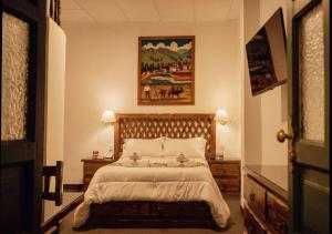 卡哈马卡El Portal Del Marques的卧室配有一张床,墙上挂有绘画作品