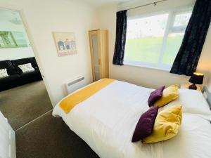 Brading2 Bedroom Chalet SB113, Sandown Bay, Isle of Wight的一间卧室配有一张大床,提供黄色和紫色枕头