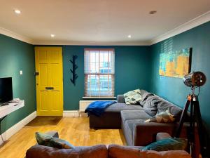 ChestertonMidsummer Cottage Cambridge的带沙发和黄色门的客厅