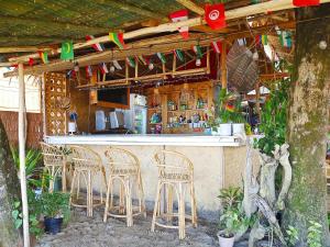 爱妮岛BH Beachfront Homestay的酒吧配有椅子和带旗帜的吧台
