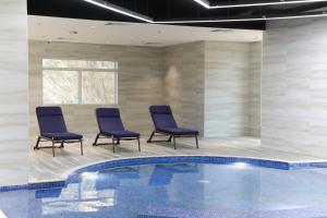 麦加TIME Ruba Hotel & Suites的一个带三把椅子和一张桌子的游泳池以及游泳池