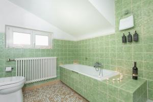 博登斯边的拉多夫采尔Bodensee-Haus IStayUnixI Seenähe-Terrasse-Garten-Netflix-Parkplatz的绿色瓷砖浴室设有浴缸和卫生间