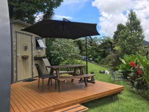 WaikinoThe Dome Waikino的木甲板上配有野餐桌和遮阳伞