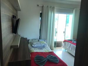 佩尼亚Pousada Ilha do Itacolomi的一间卧室配有一张床、一台电视和一个窗口