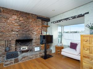布里克瑟姆Friday Cottage的客厅设有石制壁炉和电视。