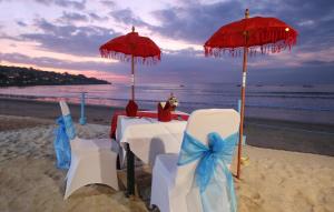 金巴兰金巴兰欧舒丹库普库普海滩Spa酒店的海滩上的桌椅和遮阳伞
