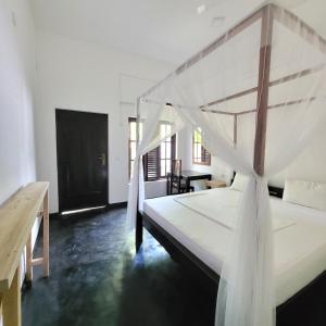阿鲁甘湾Agra Arugambay的一间卧室配有一张带天蓬的大型白色床