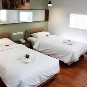 雅加达AZKA HOTEL Managed by Salak Hospitality的配有两张床铺的房间,上面有白色的床单和鲜花