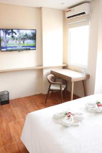 雅加达AZKA HOTEL Managed by Salak Hospitality的客房设有1张床、1张桌子和1台电视。