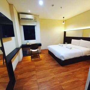 雅加达AZKA HOTEL Managed by Salak Hospitality的一间卧室配有一张床、一张书桌和一台电视