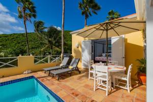 克里斯琴斯特德Seaview Palms Villa - St Croix USVI的庭院配有桌椅和遮阳伞。