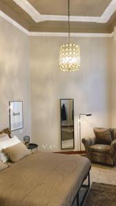 布斯托阿西齐奥Guest House Mameli44的一间卧室配有一张床、一把椅子和一个吊灯。
