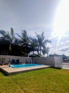 伊塔波阿Férias Perfeitas, Praia e Piscina的棕榈树庭院内的游泳池