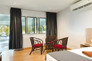 邦咯邦咯沙滩度假村的一间卧室配有两把椅子和一张床,设有窗户。