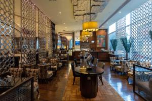 曼谷曼谷阿索克希尔顿酒店 - Hilton Bangkok Grande Asoke的一间餐厅,在房间内配有椅子和桌子