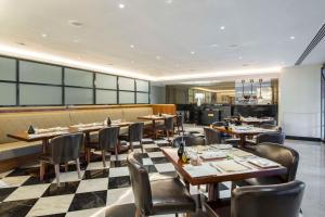 吉达The Hotel Galleria Jeddah, Curio Collection by Hilton的餐厅设有木桌和椅子,铺有 ⁇ 木地板