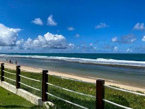 嘎林海斯港Flat Beach Class Muro Alto - Porto de Galinhas 02 Quartos的沙滩上有人在沙滩上行走的栅栏