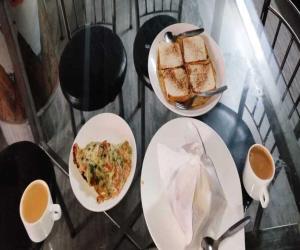 甘托克Dhe Kyi Khang by Magwave Hotels-100 Mts from MG Marg的餐桌,盘子上放着食物和咖啡