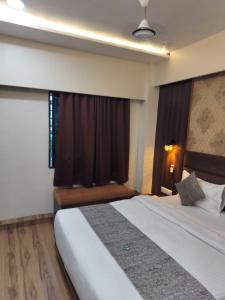 艾哈迈达巴德HOTEL RJ RESIDENCY的酒店客房设有床和窗户。