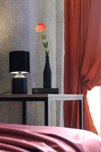 第比利斯Round Garden Hotel的花瓶,桌子上有一朵花,灯