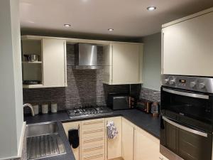 LemingtonBoss Breaks- Newcastle的厨房配有白色橱柜和炉灶烤箱。
