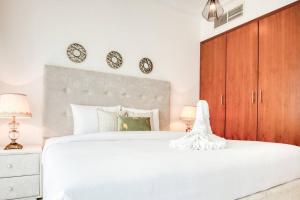迪拜Lovely 1 bedroom apartment for vacations的卧室配有白色的床和墙上的2个钟
