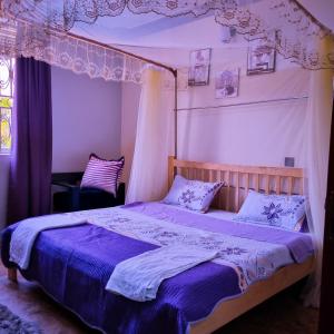 坎帕拉OCTA HOMES的一间卧室配有一张带紫色床单的天蓬床