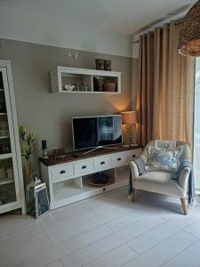 米兹多洛杰Apartament Prestige & Sea Playa Baltis 44的客厅配有电视和椅子