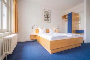 魏玛阿尔特维马尔酒店的一间卧室配有一张大床,铺有蓝色地毯