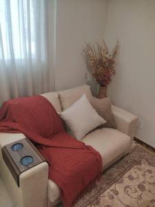 巴西利亚Apartamento Aconchegante的一张带毯子的沙发,上面有一个遥控器