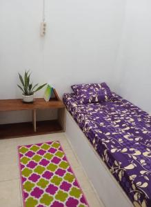 SintangGreenKOST的一张床位,位于带桌子和地毯的房间里