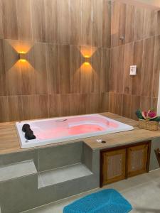 阿廷斯POUSADA IRMAOS ATINS的木墙上配有带灯的粉红色浴缸