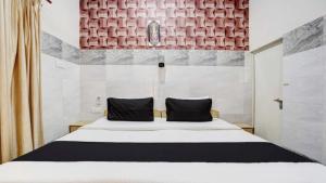 阿格拉Pyrenees Homestay的卧室配有带黑色枕头的白色床
