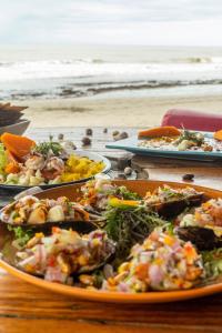 曼克拉Wiracocha Hostal Máncora - Surf Camp的海滩上一张带食物盘的桌子