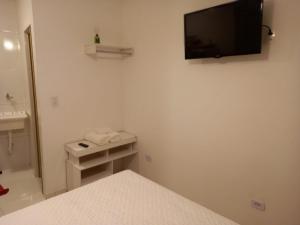 瓜鲁雅Suíte Studio 3 Enseada Tortuga Mobiliada的卧室配有一张床,墙上配有电视